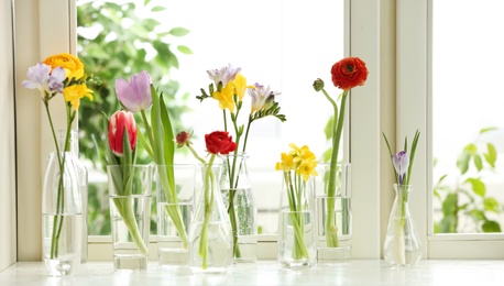 Beautiful spring flowers in glassware on window sill
