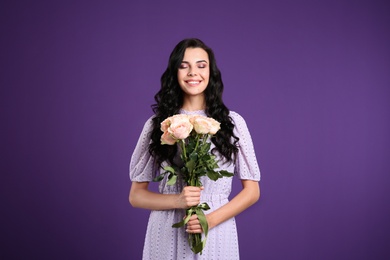 Portrait of smiling woman with beautiful bouquet on purple background