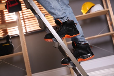 Person climbing ladder indoors, closeup on feet