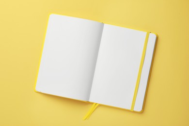 Blank notebook on pale yellow background, top view
