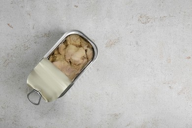 Photo of Open tin can of tasty cod liver on textured table, top view. Space for text