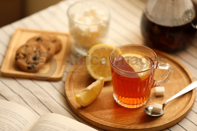 Glass mug of aromatic tea with lemon and sugar on table. Space for text