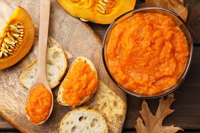 Slices of bread with delicious pumpkin jam and fresh pumpkin on wooden table, flat lay