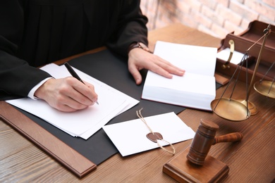 Judge working with papers at table in office, closeup. Law and justice concept
