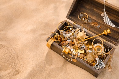 Open wooden treasure chest on sand, above view. Space for text