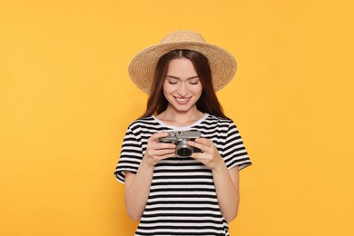 Young woman with camera on yellow background. Interesting hobby