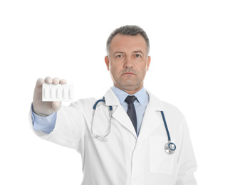 Doctor holding suppositories for hemorrhoid treatment on white background
