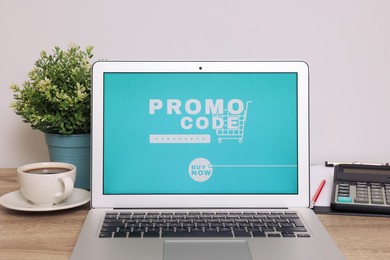 Photo of Laptop with activated promo code on wooden table indoors