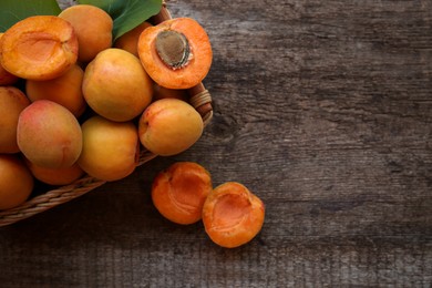 Photo of Basket with delicious ripe apricots on wooden table, top view. Space for text