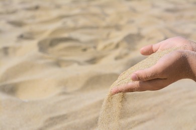 Child pouring sand from hand outdoors, closeup with space for text. Fleeting time concept