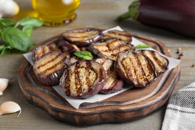 Delicious grilled eggplant slices served on wooden table, closeup