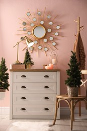 Stylish room interior with dresser and small fir trees