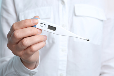 Photo of Woman holding modern digital thermometer, closeup view
