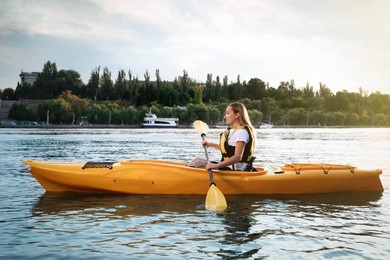 Beautiful young woman kayaking in river. Summer activity