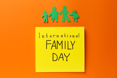 Paper cutout and card with text International Family Day on orange background, flat lay