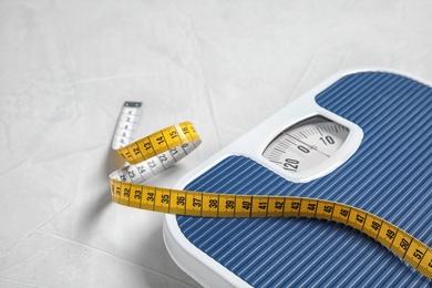 Scales and measuring tape on light background with space for text. Weight loss