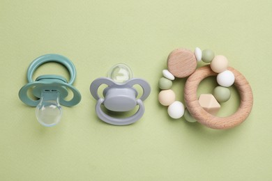 Photo of Flat lay composition with pacifiers and other baby stuff on pale green background. Space for text