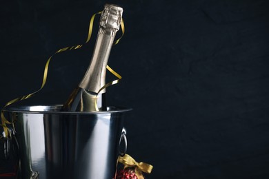 Happy New Year! Bottle of sparkling wine in bucket on black background, space for text