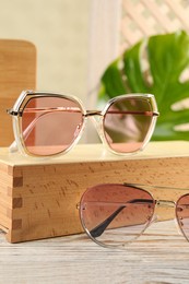 Stylish sunglasses on white wooden table. Summer accessories