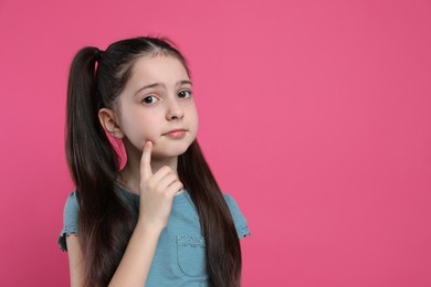 Pensive little girl on pink background, space for text. Thinking about answer to question