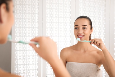 Woman brushing teeth in front of mirror at home