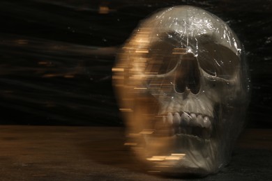 Photo of Human skull with stretch film on stone surface against black background. Space for text
