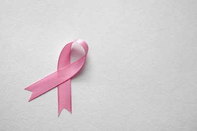 Pink ribbon on white background, top view with space for text. Breast cancer awareness concept