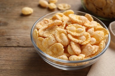 Photo of Bowl with tasty corn flakes on wooden table, closeup