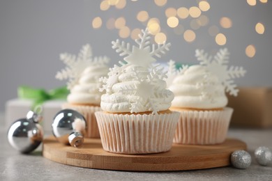 Tasty Christmas cupcakes with snowflakes on grey table