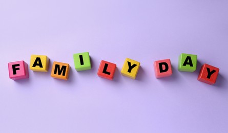 Colorful cubes with text Family Day on violet background, flat lay