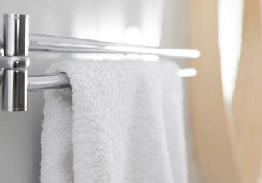 Holder with clean towel on light wall in bathroom, closeup