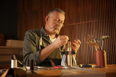 Man sewing piece of leather in workshop