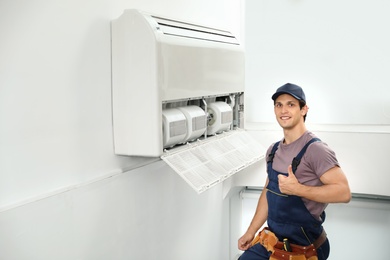 Male technician standing near air conditioner indoors