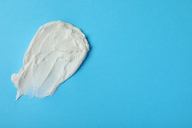 Smear of delicious cream cheese on light blue background, top view. Space for text
