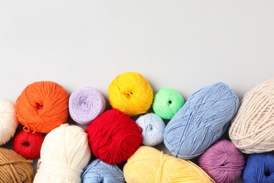 Different colorful woolen yarns on white background, flat lay. Space for text