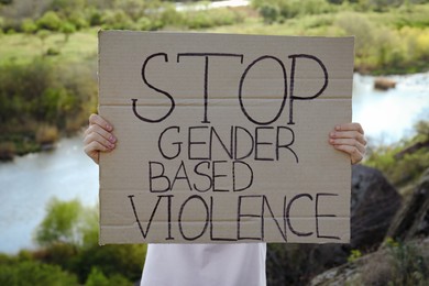 Photo of Woman holding sign with text Stop Gender Based Violence outdoors