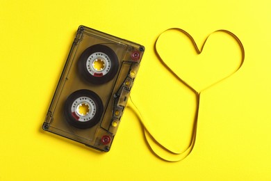 Music cassette and heart made with tape on yellow background, top view. Listening love song