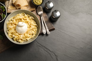 Delicious pasta with burrata cheese served on black table, flat lay. Space for text