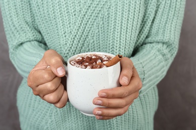 Woman holding cup of delicious hot cocoa drink with marshmallows, closeup