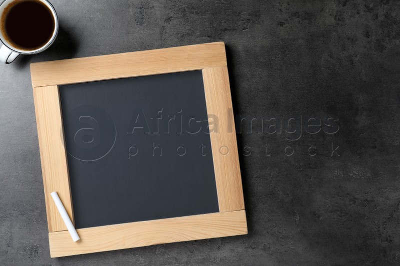Clean small chalkboard and cup of coffee on grey table, flat lay. Space for text