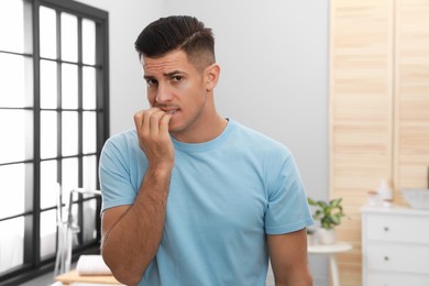 Man biting his nails indoors. Bad habit