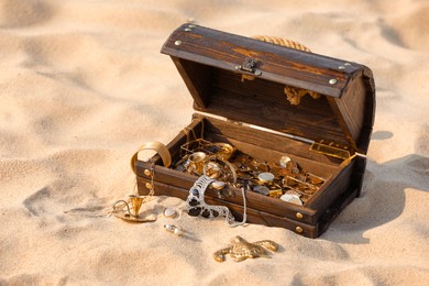 Open wooden treasure chest on sand outdoors