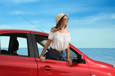 Happy woman leaning out of car window on beach. Summer vacation trip