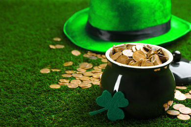 Pot of gold coins and clover on green grass, space for text. St. Patrick's Day celebration