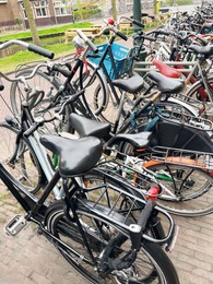Many different bicycles parked on sidewalk, closeup