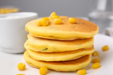 Tasty corn pancakes with sweet kernels and sauce served on table, closeup