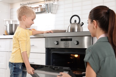 Young woman and her son baking cookies in oven at home