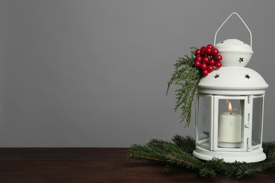 Christmas lantern decorated with coniferous twigs and berries on grey background, space for text