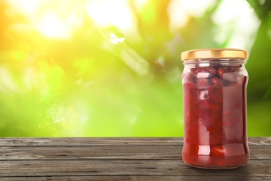 Jar of pickled beans on wooden table against blurred background, space for text