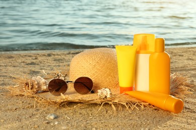 Sun protection products and beach accessories on sand near sea, space for text